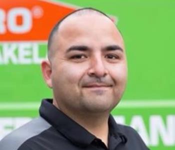 Male employee smiling in front of a SERVPRO vehicle