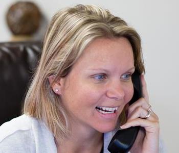 Female employee answering phone and smiling in front of a white background