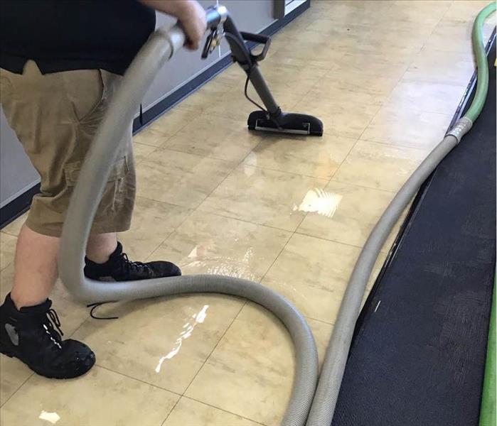 Man extracting water from tile floor.