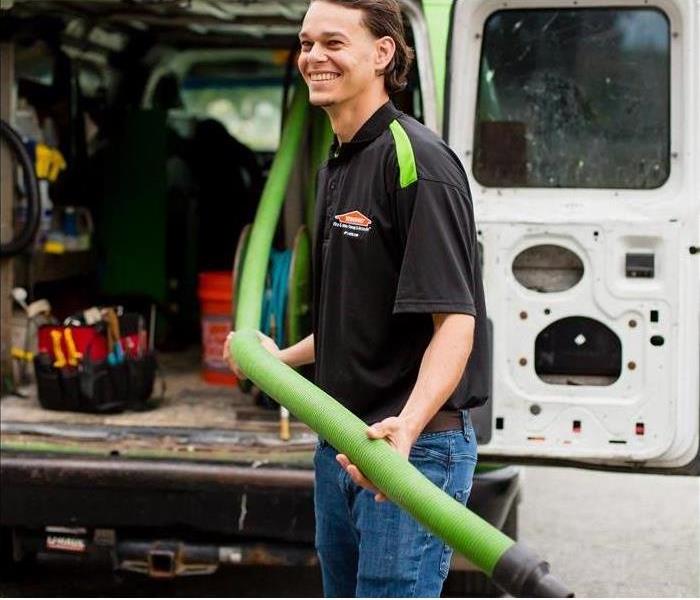 SERVPRO technician in front of SERVPRO vehicles
